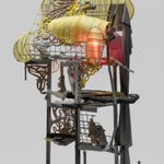 A floor lamp made from steel and wire baskets with ovular, yellow fabric shades and a red-tinted bulb.