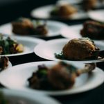 Rows of white plates of food: with a drumstick and greens