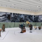 Collection of handmade art sculptures made from various materials, displayed in front of large black and white paintings in an exhibit at the Walker Art Center