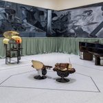 Three handmade art sculptures displayed in front of two large black and white paintings in an exhibit at the Walker Art Center