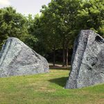 Two large rock like sculptures sit in a grass lawn.