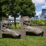 A sculpture of two reclining figures sits in a garden overlooking a city.