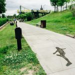 Concrete sidewalk with a faint image of a person etched into the cement. Green grass pathway surrounds the sidewalk and figure.