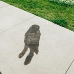 Concrete sidewalk with a faint image of a person etched into the cement.