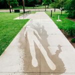 Concrete sidewalk with a faint image of a person etched into the cement.