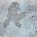 Concrete sidewalk with a faint image of a person etched into the cement.