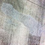 Concrete sidewalk with a faint image of a person etched into the cement.
