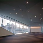 A empty large event space at the Walker Art Center with big windows and small round ceiling lights